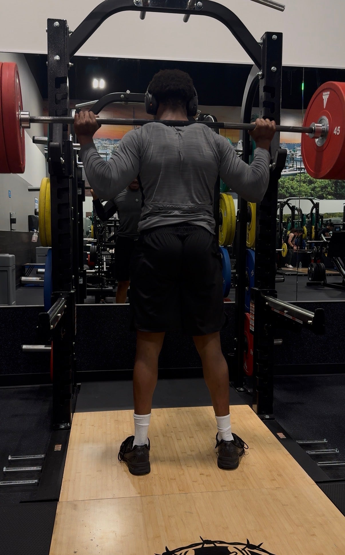 Person performing squats with a barbell in a gym setting